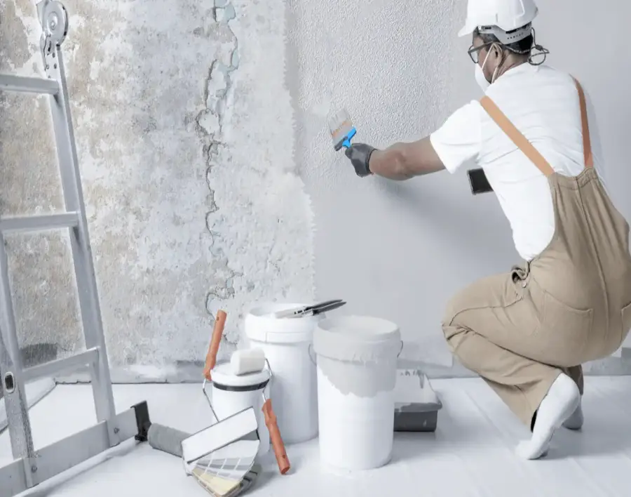 Expert repairing a damp, damaged wall before waterproofing