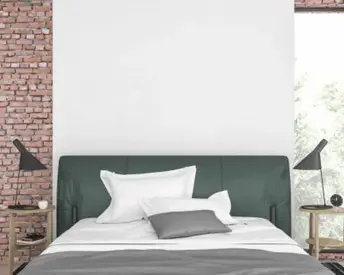 Modern bedroom with exposed brick wall and dark green headboard