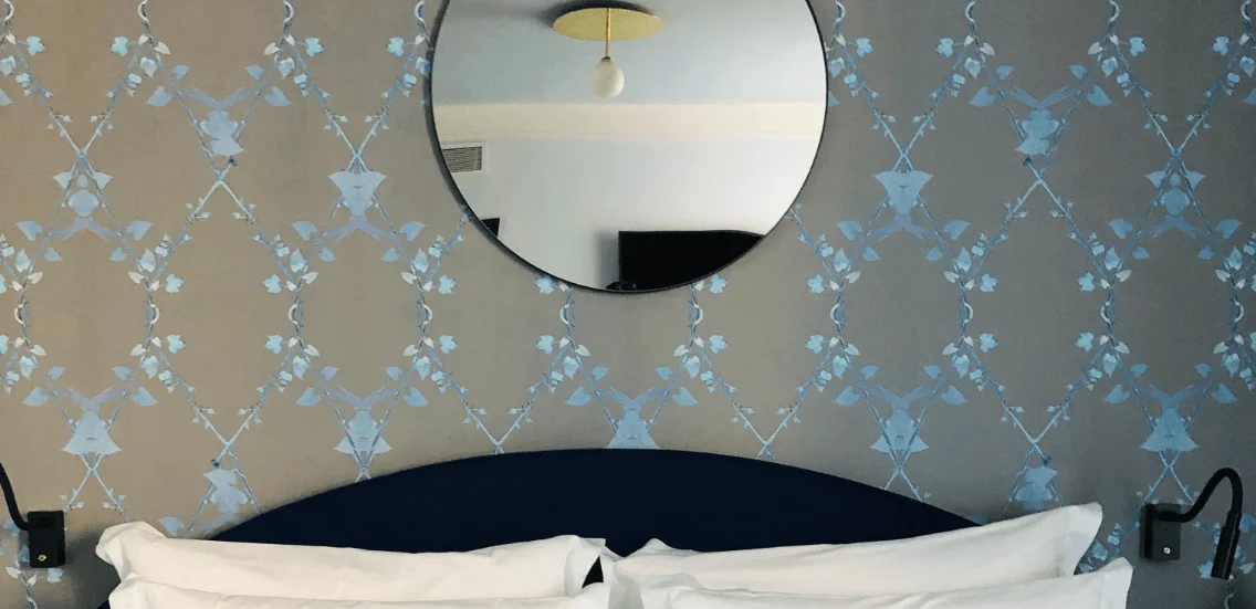 Metallic stencil bedroom wall with round mirror