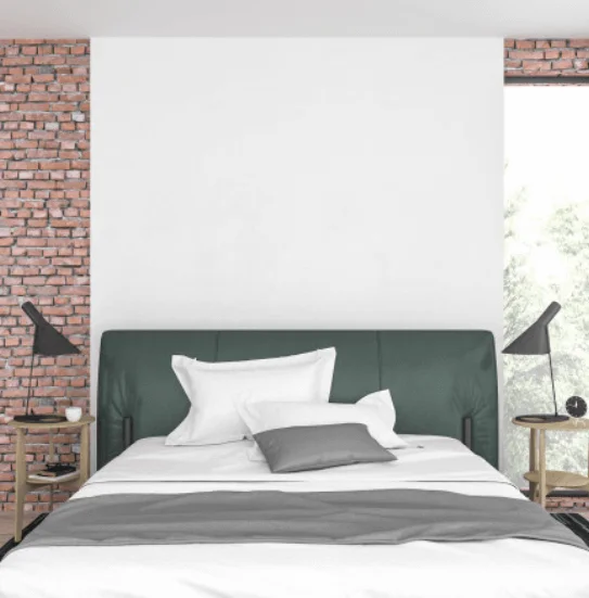 Modern bedroom with exposed brick wall and dark green headboard